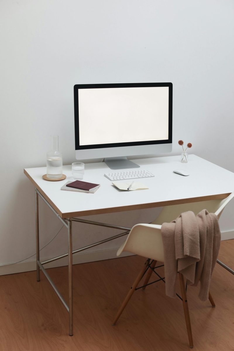 A clean, contemporary home office setup with a white desk, monitor, and minimal decor.