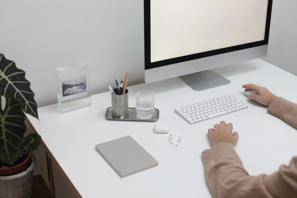 High angle of crop faceless person sitting at table with wireless gadgets and computer